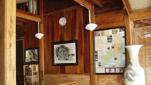 A room with wooden beams, a large map on the wall, and several wicker chairs. - Cat Tien Farm Stay (Nam Cat Tien)
