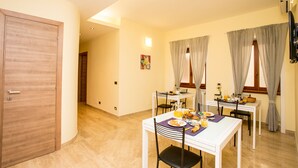 A dining area with a table set for breakfast, a wooden door, and a TV mounted on the wall. - Trastevere's Friends (Rome)