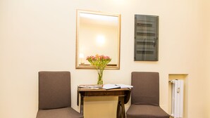 A room with two chairs, a small table with a vase of flowers, a mirror, and a wall-mounted electrical panel. - Trastevere's Friends (Rome)