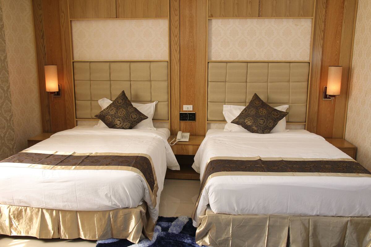 A double room with two beds, each with a headboard, bedside lamps, and a telephone.