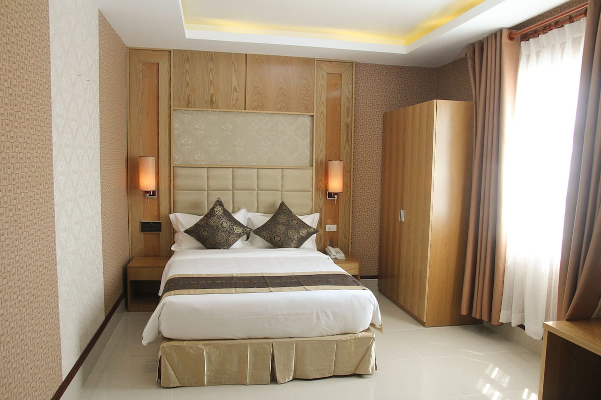 A large bed with a headboard, bedside lamps, and a wooden wardrobe.