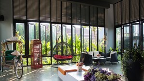A modern interior with a bicycle, a red telephone booth, and a wicker chair. - Milano Hua Hin (Hua Hin)