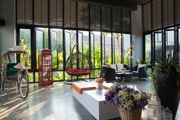 A modern interior with a bicycle, a red telephone booth, and a wicker chair.