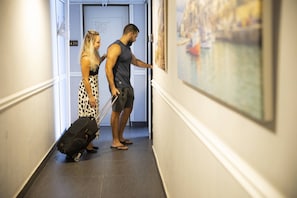 A hallway with a door labeled "216" and a painting of a cityscape on the wall. - Miami Beach Hotel Tel Aviv (Tel Aviv)
