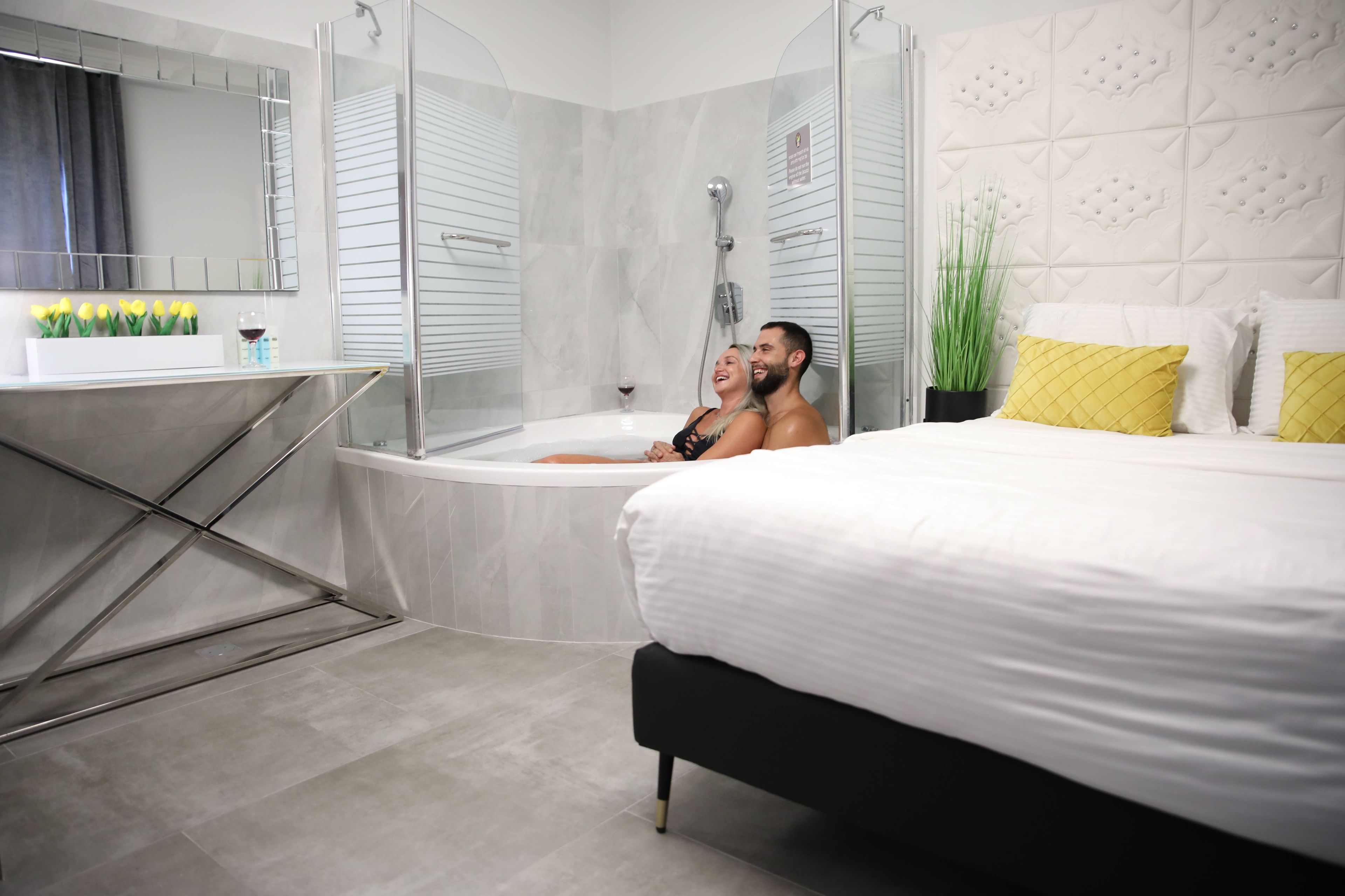 A modern bathroom with a glass-enclosed shower, a bathtub, and a vanity with a mirror and toiletries.