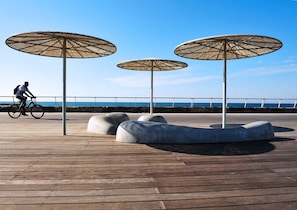 Stroll along the boardwalk, offering scenic ocean views and shaded areas beneath three large umbrellas.