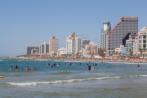 Una playa con surfistas y el perfil urbano del fondo.