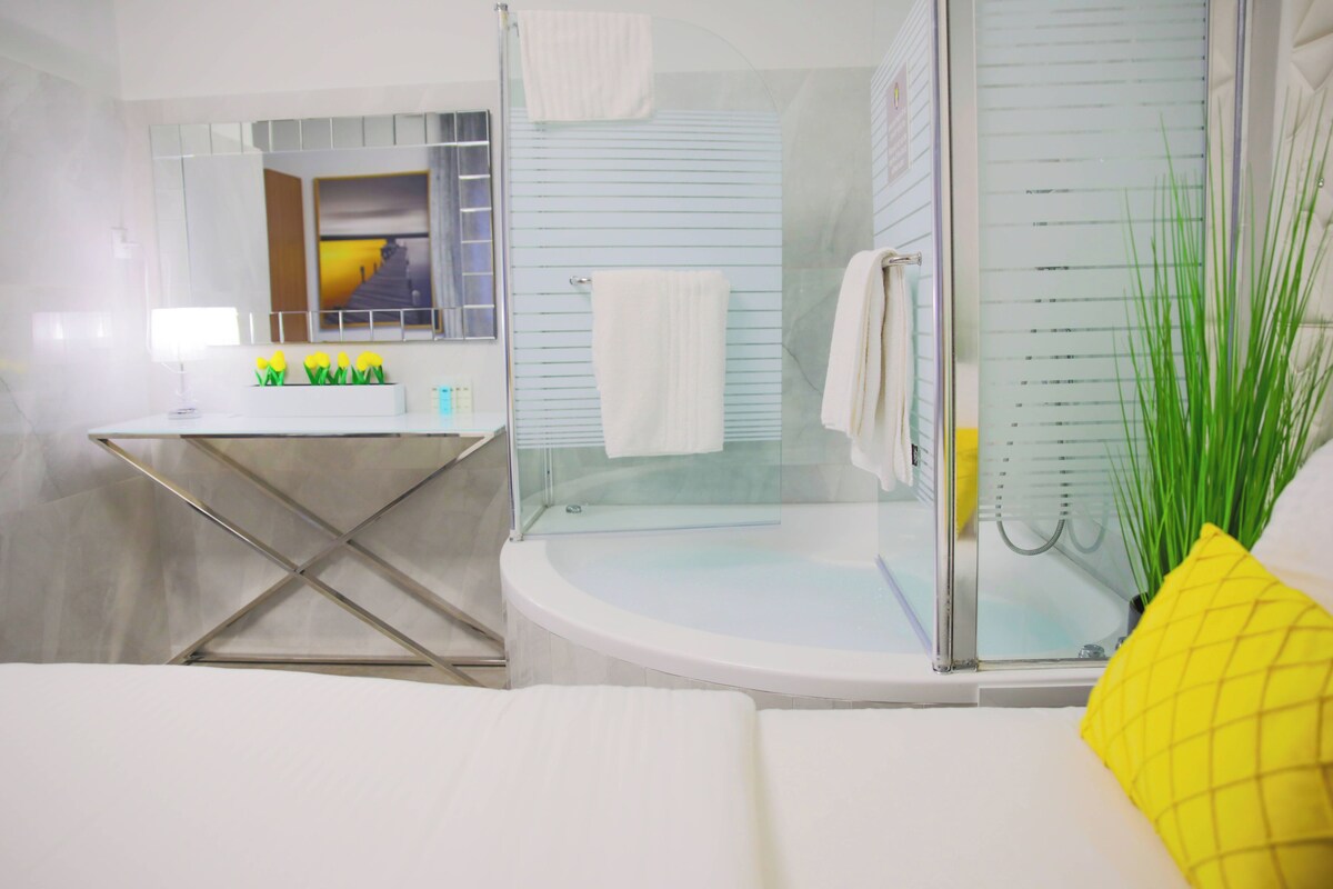 A modern bathroom with a glass shower enclosure, a white bathtub, and a vanity with a mirror.