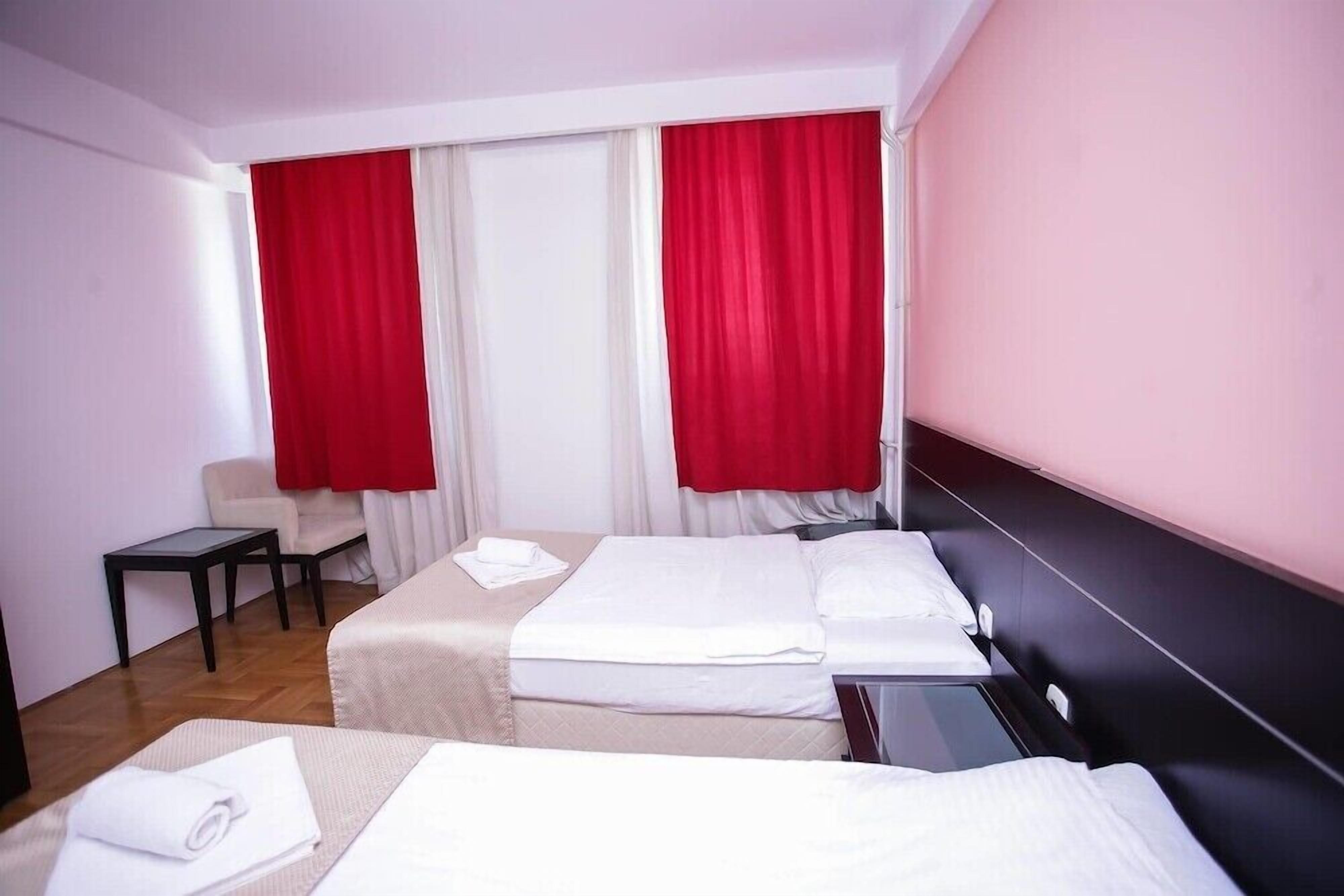 A hotel room with two beds, a small table, and a chair.