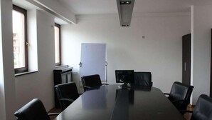 Ett konferensrum med ett långt bord, svarta stolar, en whiteboard och en dörr.