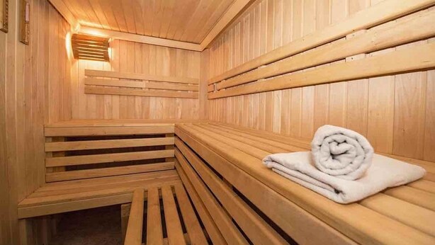 A wooden sauna with benches and a bench with a towel. - Hala Inn Hotel Apartments (Ajman)