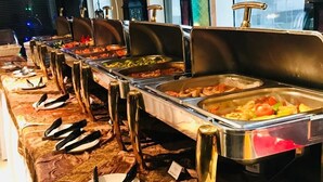 A buffet setup with multiple serving stations, each with a variety of dishes. - Hala Inn Hotel Apartments (Ajman)