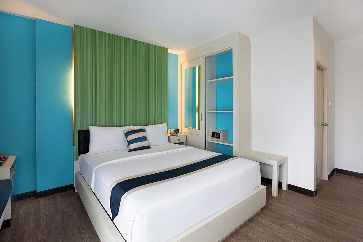 Ein modernes Hotelzimmer mit einem großen Bett, Nachttischen, einem Beistelltisch und einem Schrank mit Spiegel.