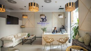 A hotel reception area with a sofa, two wicker chairs, a reception desk, and a large plant. - Soho Boutique Malaga (Málaga)