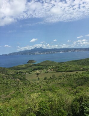 A coastal landscape with a mountain in the background, a clear sky, and a view of the sea.