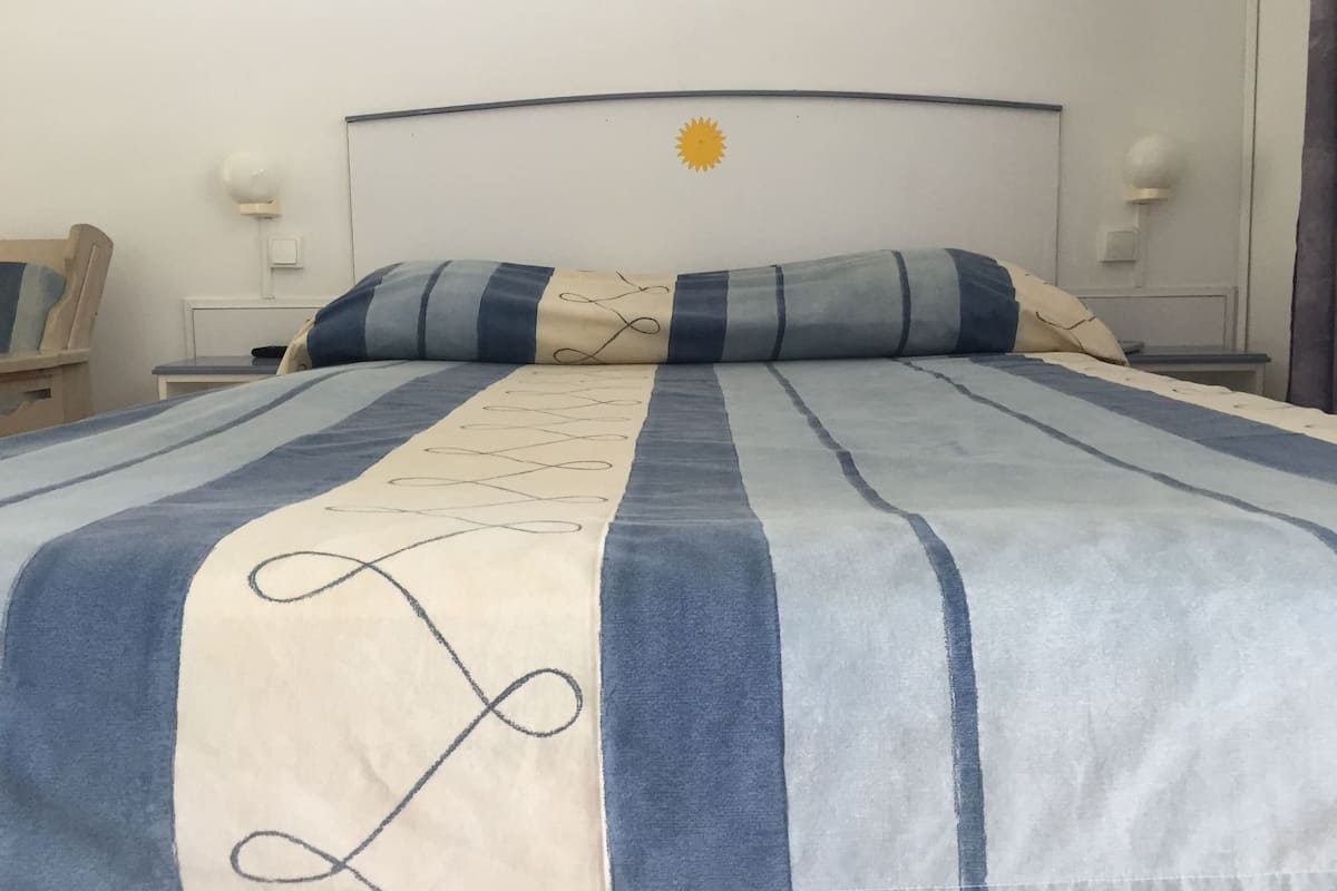 A bed with a striped bedspread and a decorative pillow.