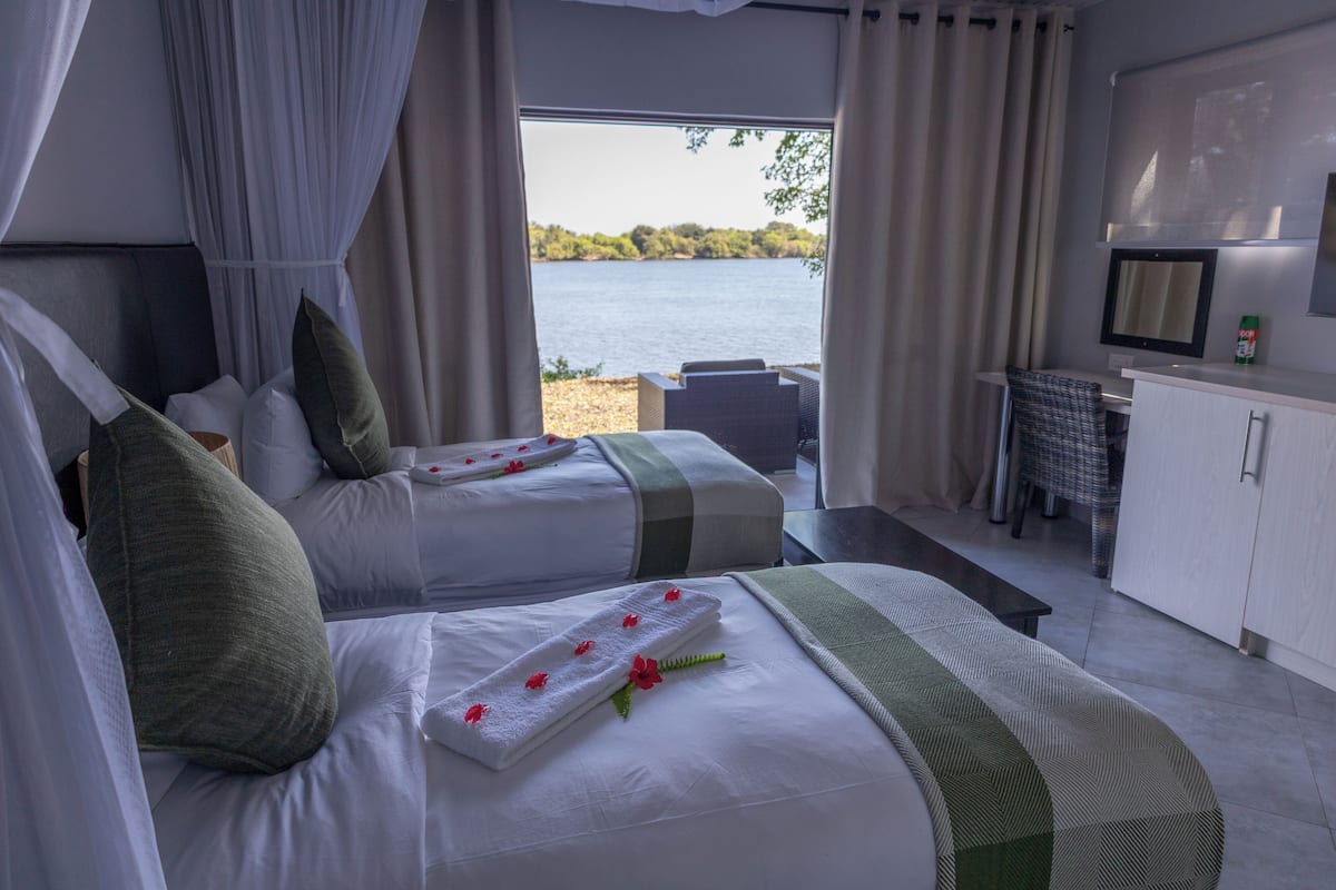 A bedroom with two beds, a desk, and a view of a lake.