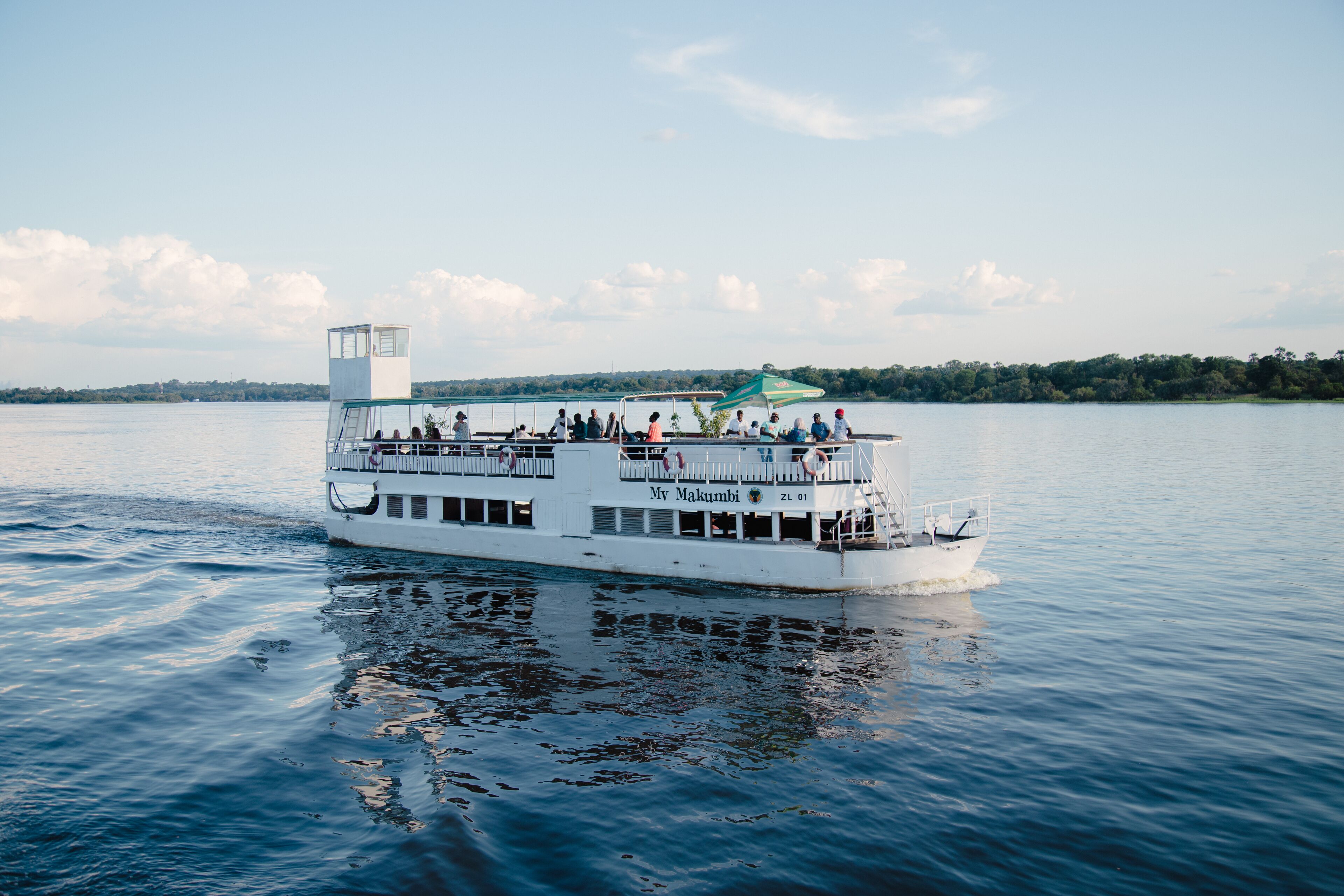 A white riverboat with multiple decks and a covered upper deck, named "My Makumbi."