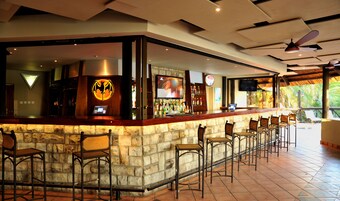Un área de bar con mostrador de piedra, taburetes y una pantalla de televisión.