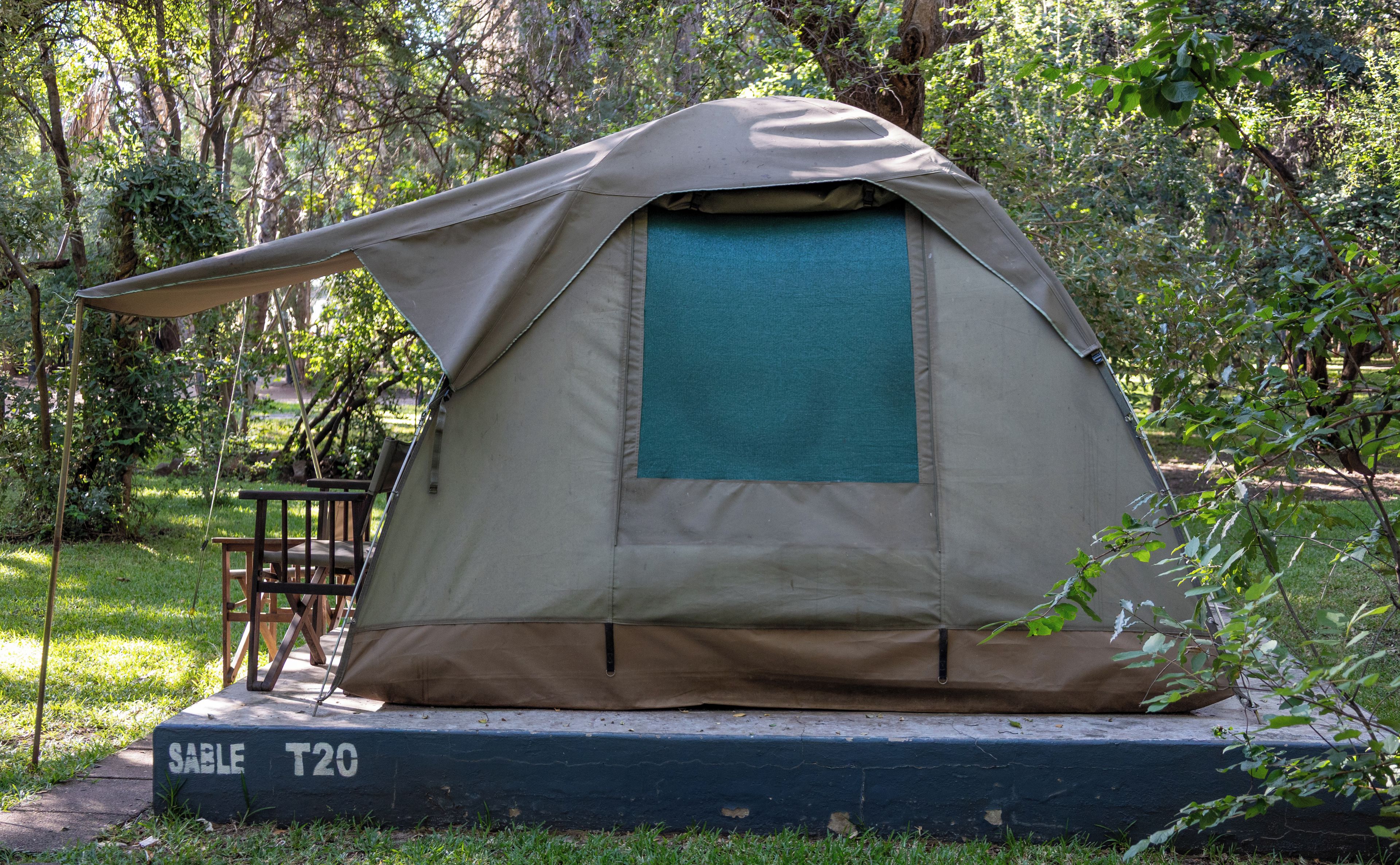 A tent with a table and chair set up on a platform labeled 'SABLE T20' in a wooded area.