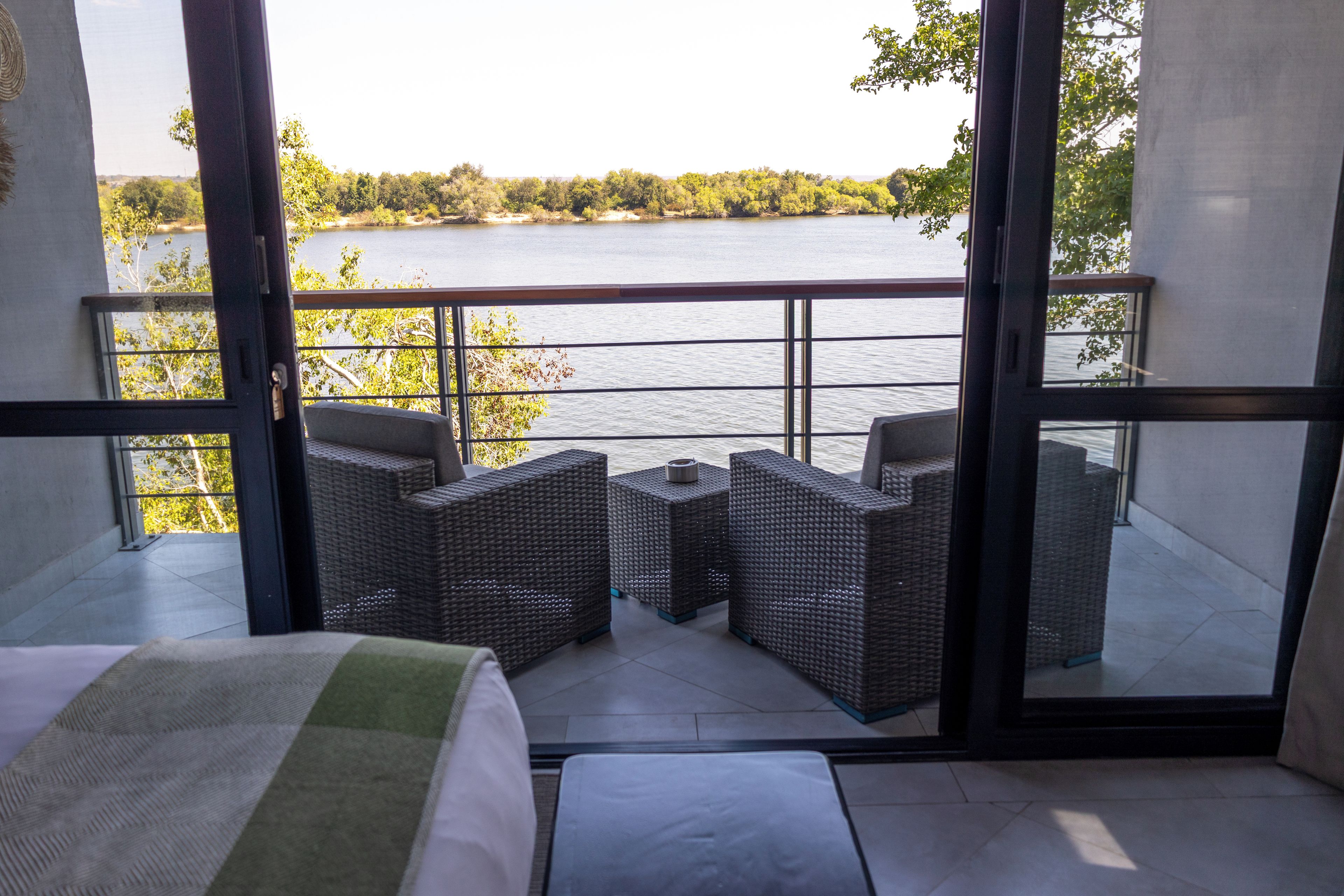 A balcony with wicker furniture overlooking a body of water.