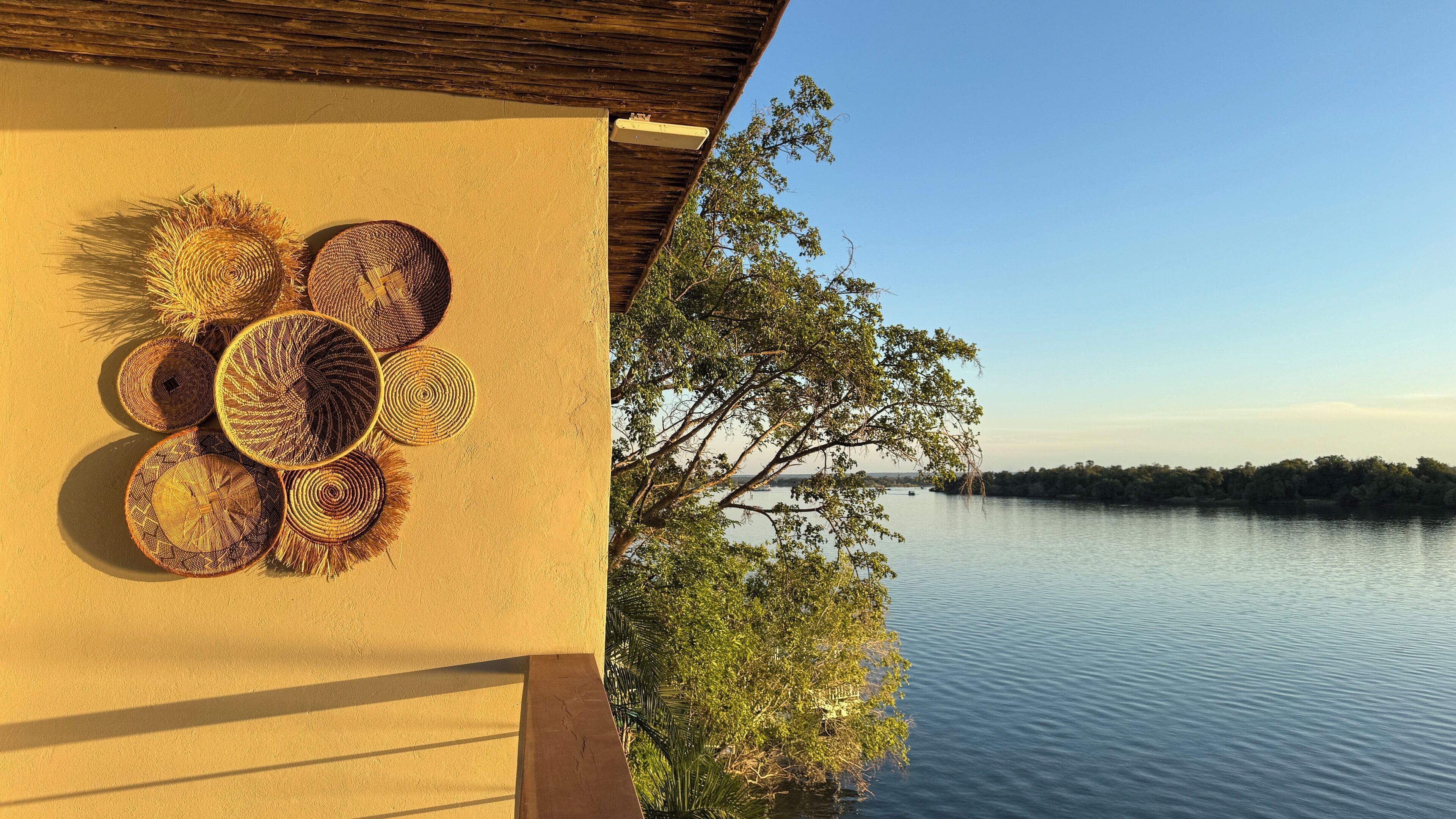 En vy över en stilla sjö med en träkonstruktion och flätade korgar på väggen.