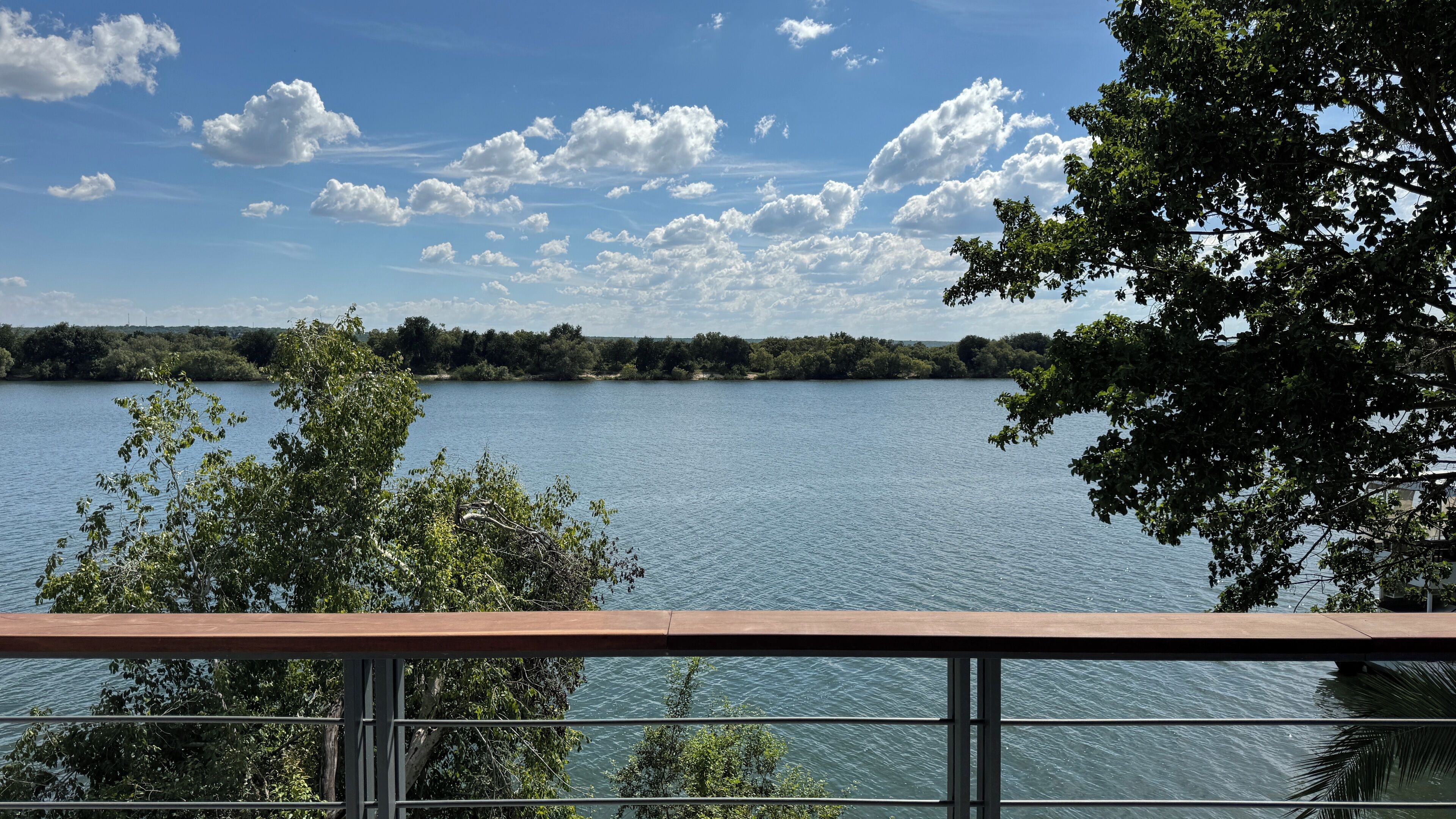 Un lac, avec un ciel dégagé et des arbres au premier plan.