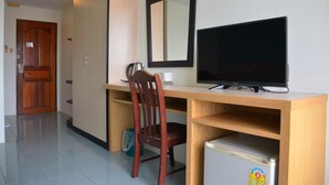 Een compacte hotelkamer met een houten bureau, een televisie, een stoel en een kleine koelkast.