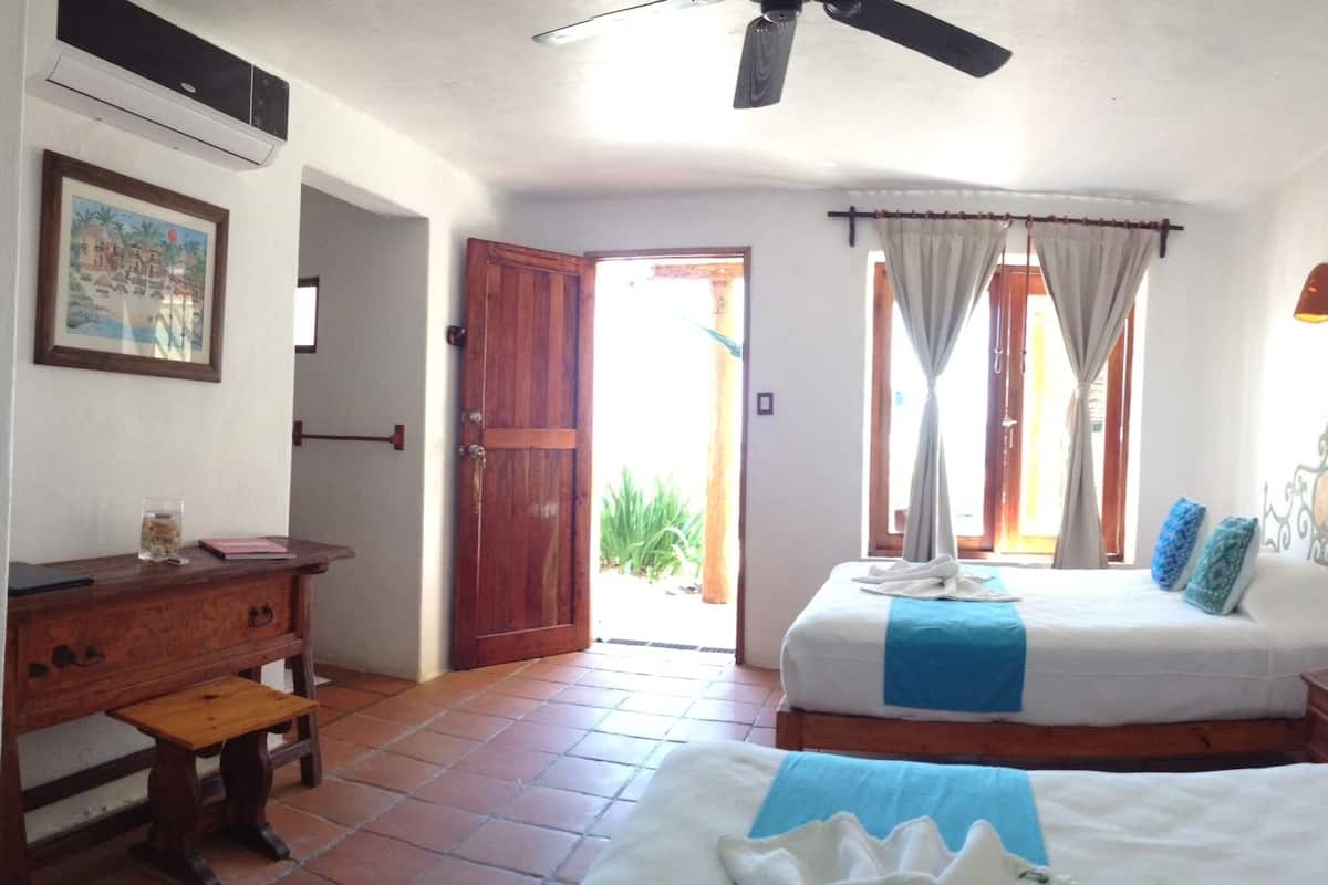 A bedroom with a bed, bedside tables, a wooden dresser, a ceiling fan, and a door leading to a balcony.