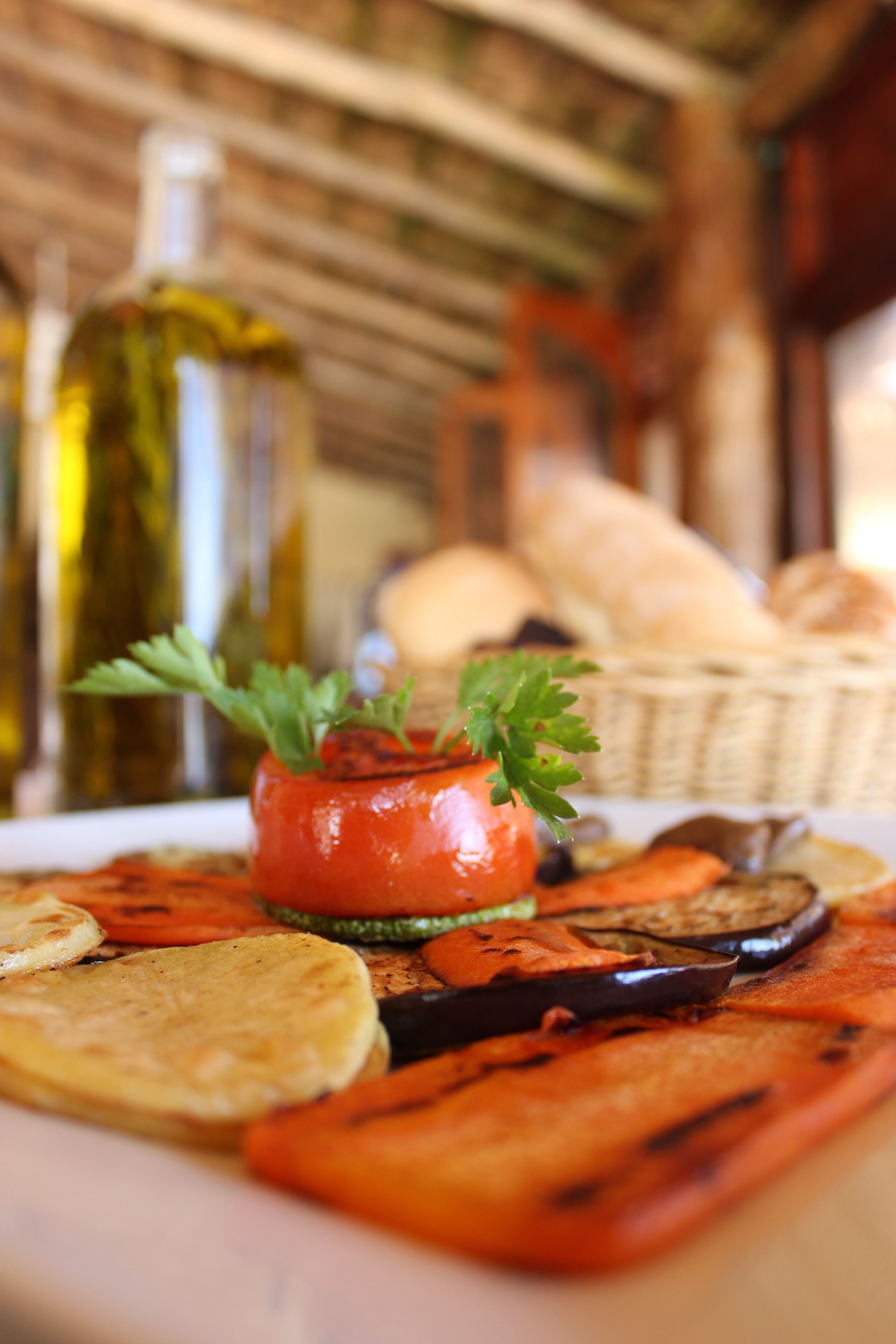A plate of grilled vegetables and a bottle of olive oil.