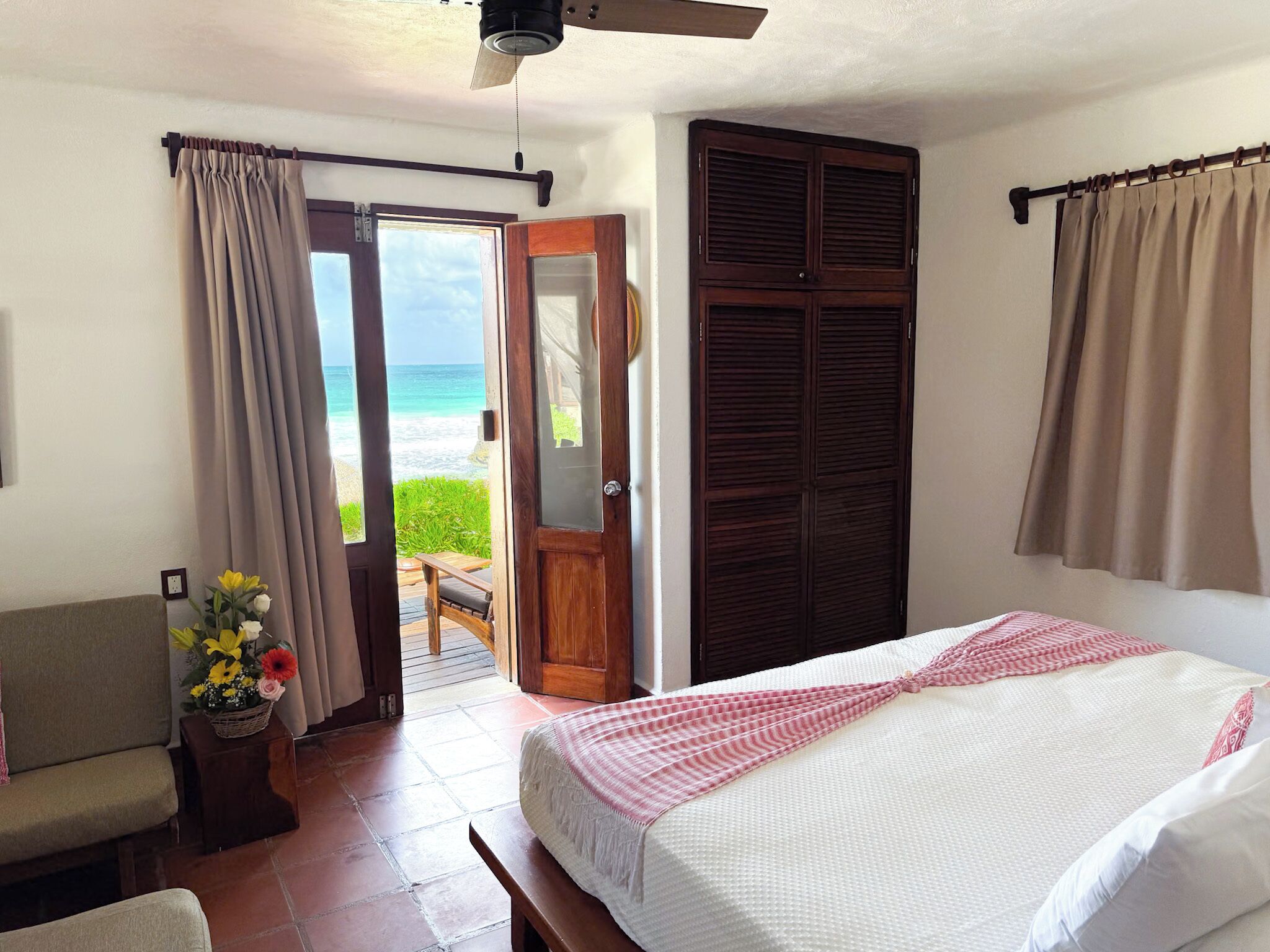 Une chambre avec un lit, une chaise, une porte en bois et une vue sur la plage.