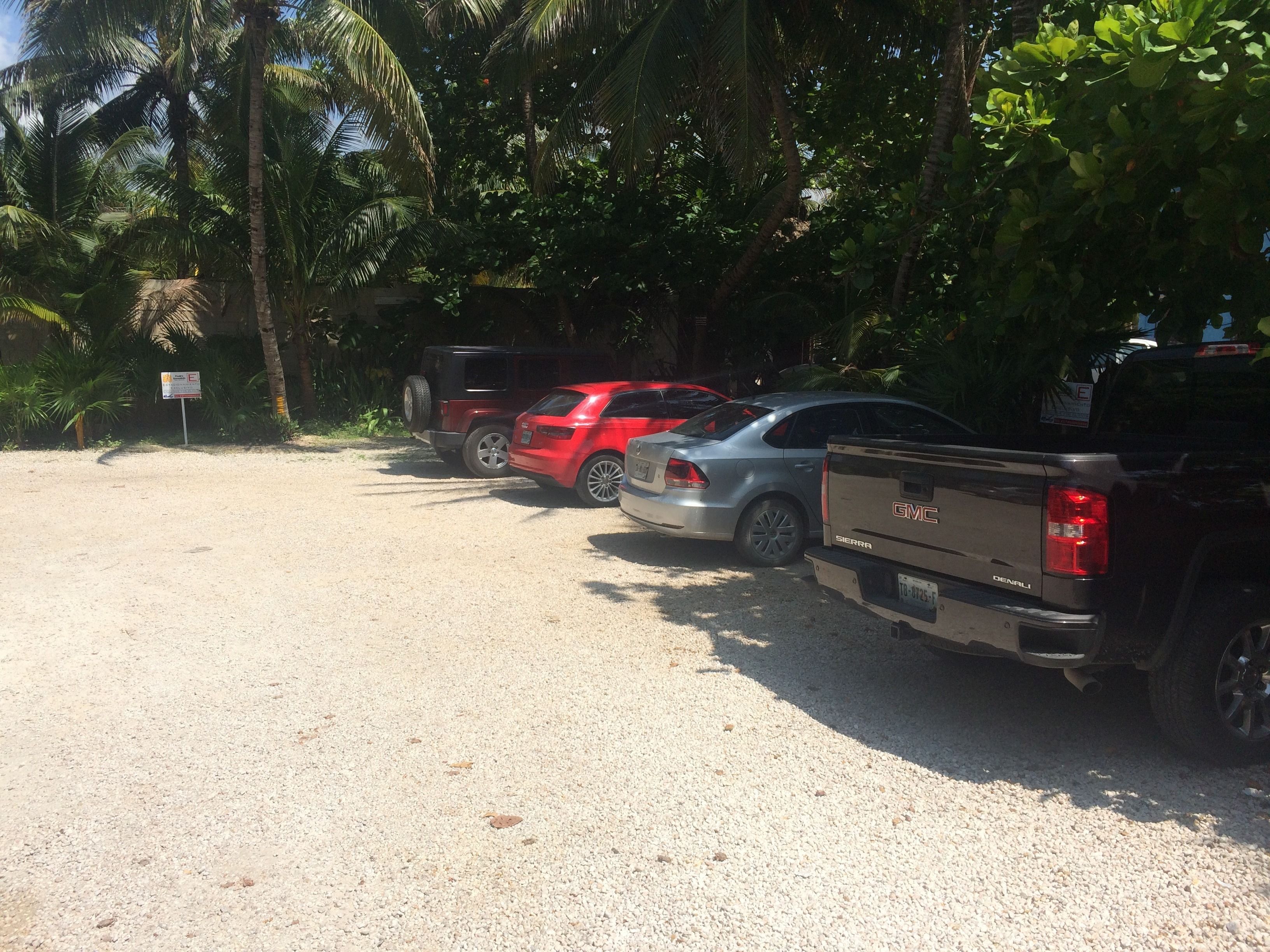 A parking area with several vehicles, including a red car and a GMC Sierra truck.