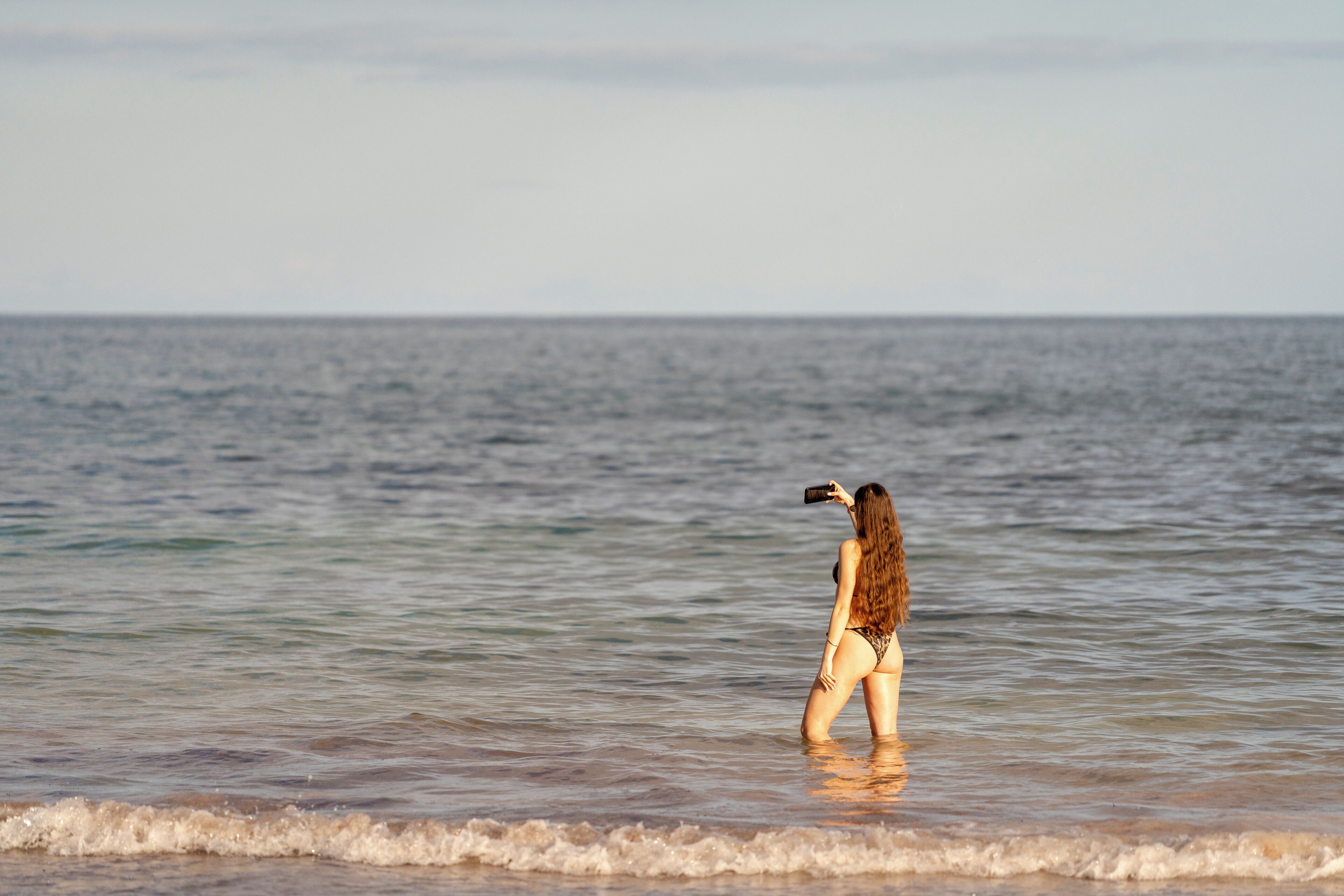 Una persona de pie en aguas poco profundas en la playa.