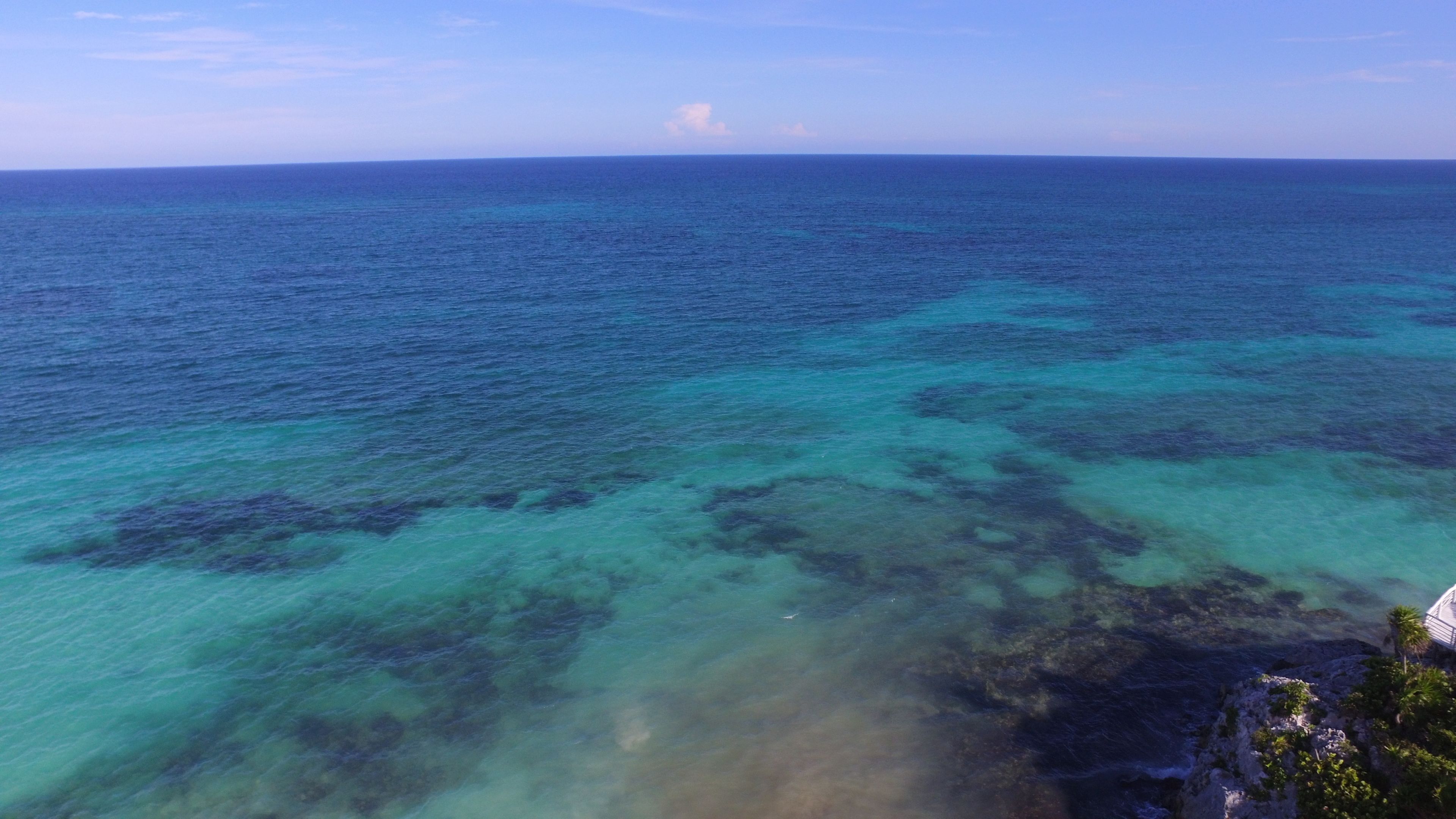 Kustgezicht met helder turquoise water en rotsformaties.