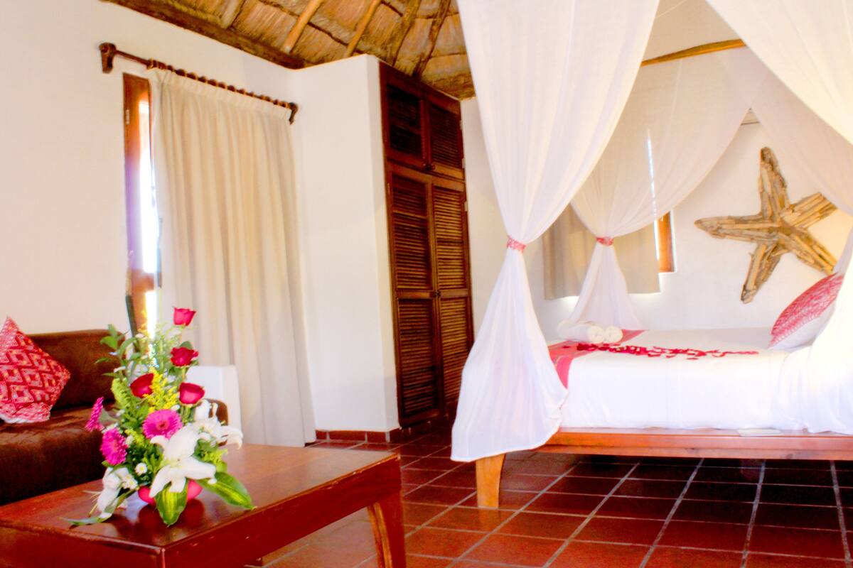 A room with a bed, a nightstand, a table with a vase of flowers, and a starfish decoration on the wall.