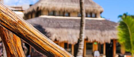 A thatched-roof building with a clear view of the beach and palm trees in the foreground.