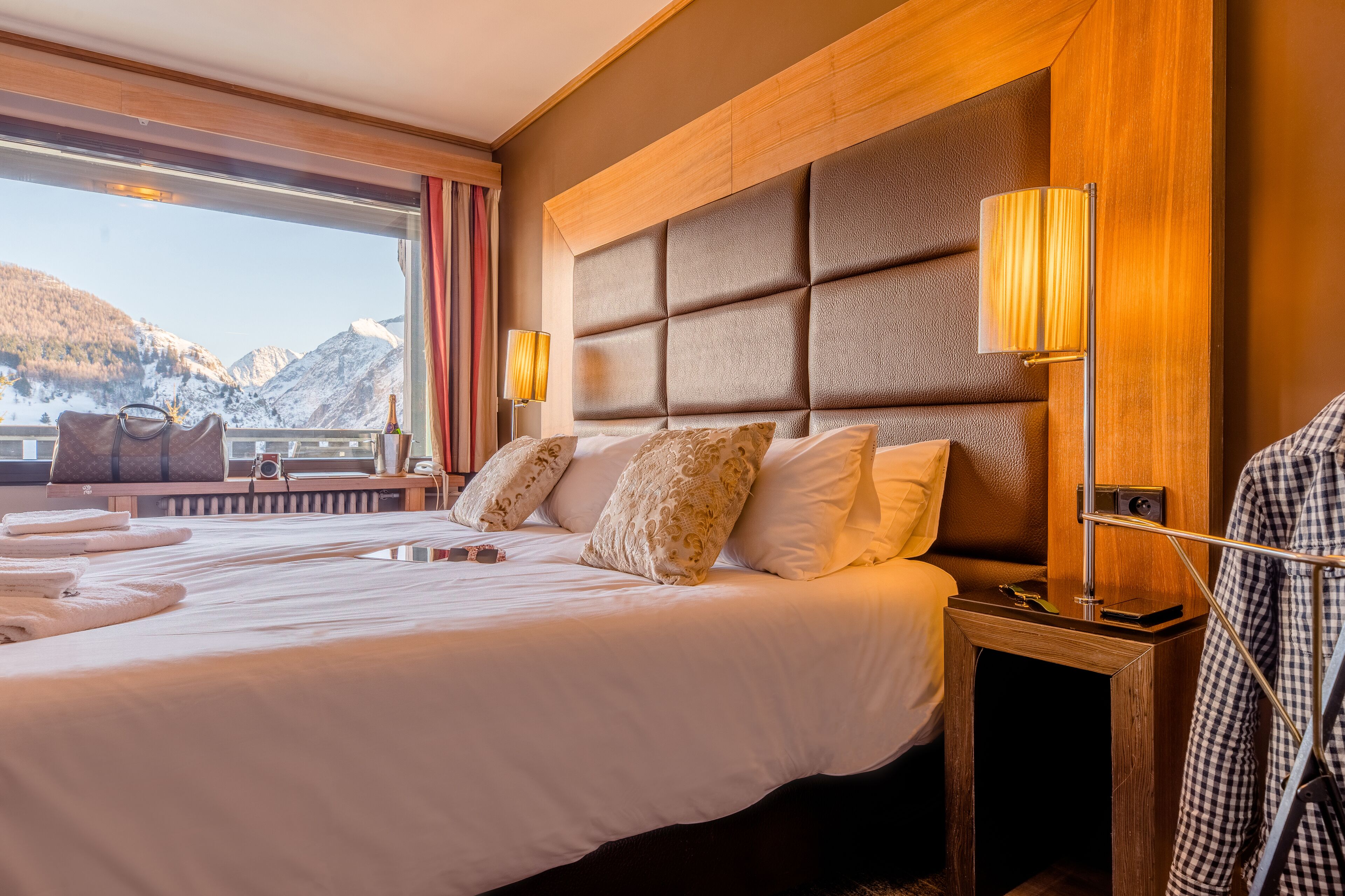 Una habitación de hotel con una cama grande, vistas a las montañas y un cabecero de madera.