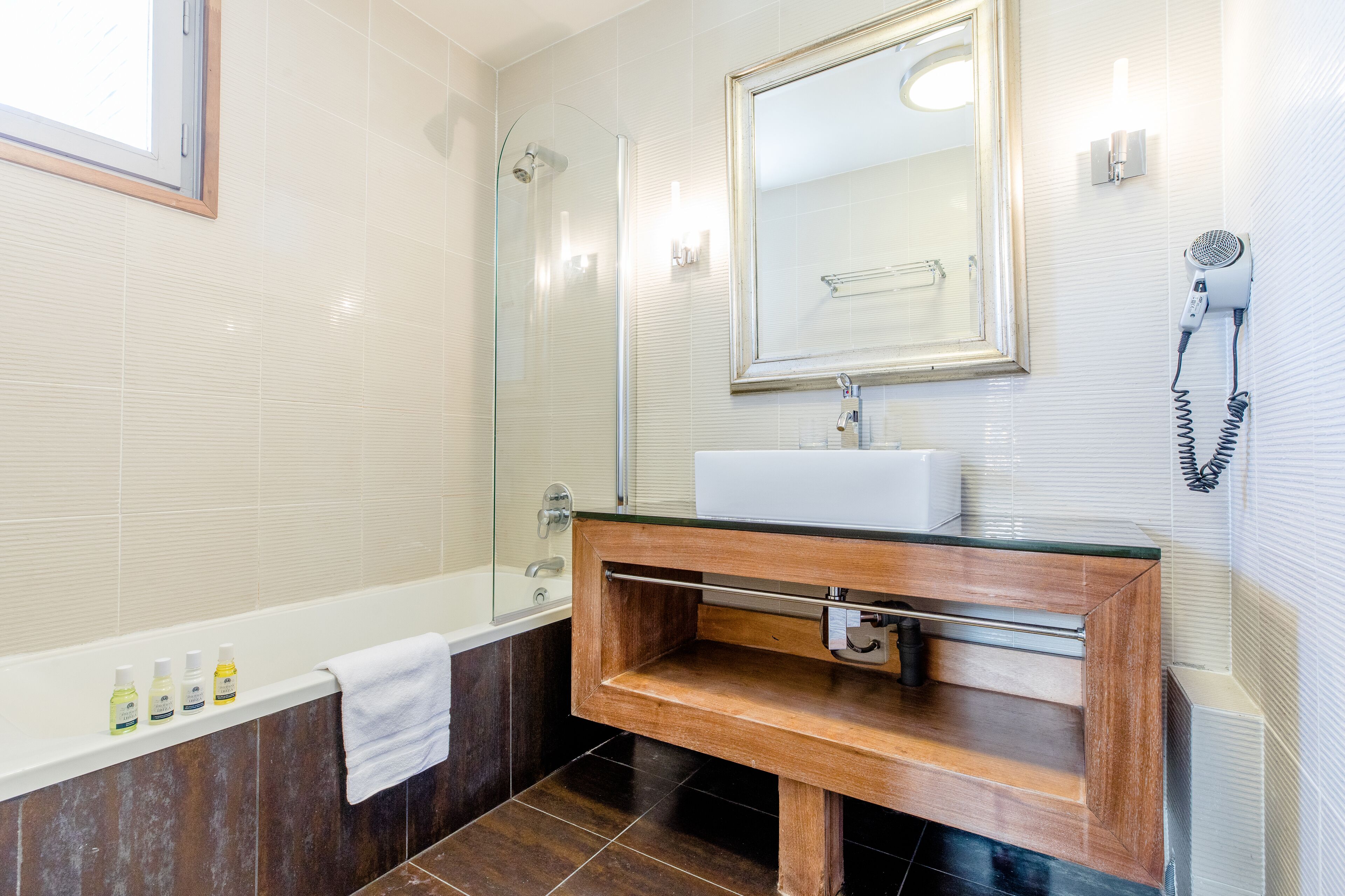 A modern bathroom with a wooden vanity, a glass shower enclosure, and a large mirror above the sink.