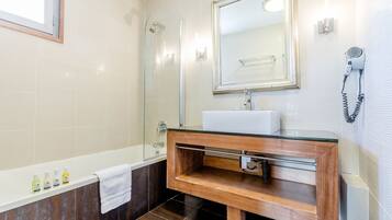 A modern bathroom with a wooden vanity, a glass shower enclosure, and a large mirror above the sink.
