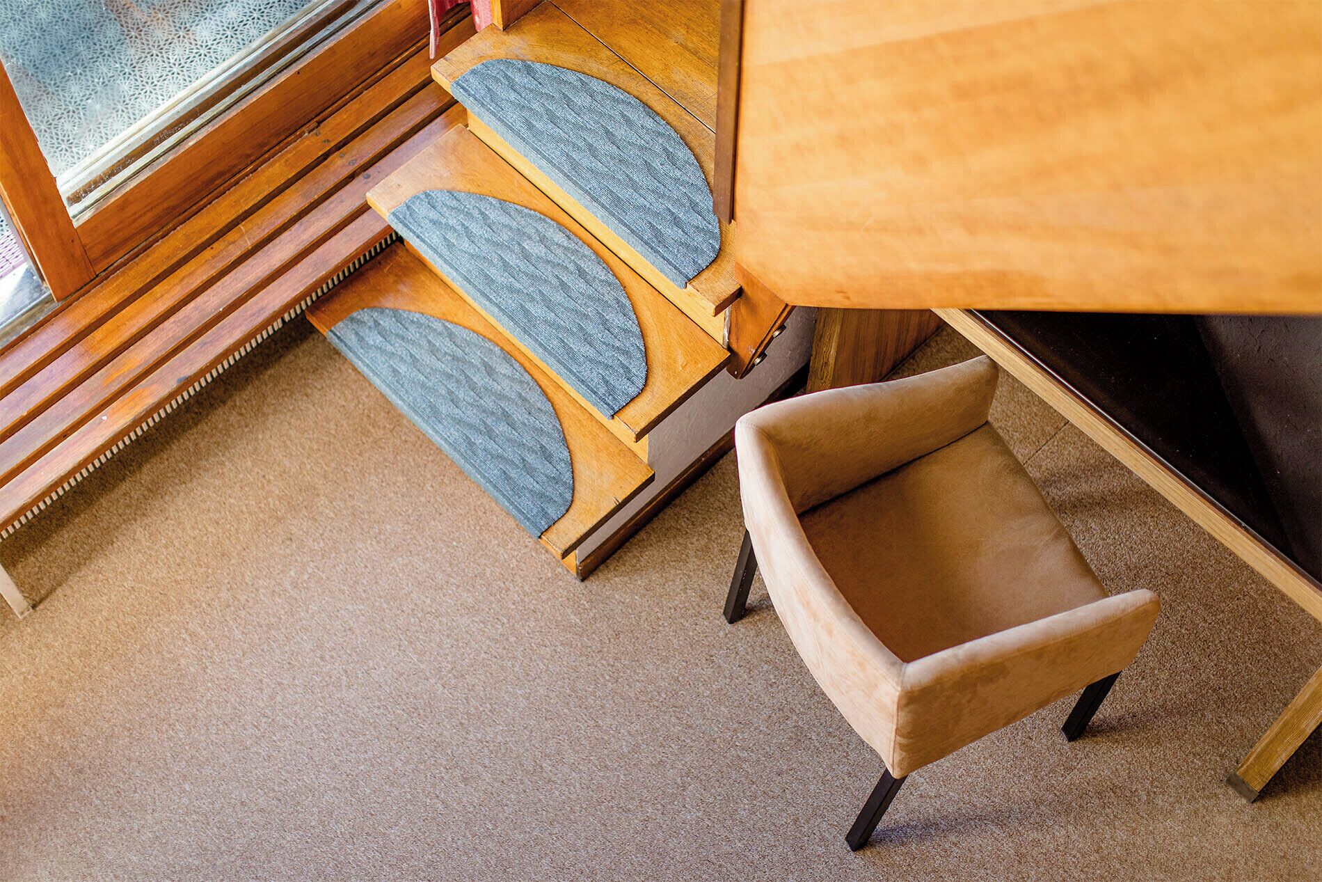 A wooden chair with a cushioned seat and backrest, a wooden table, and a carpeted floor.