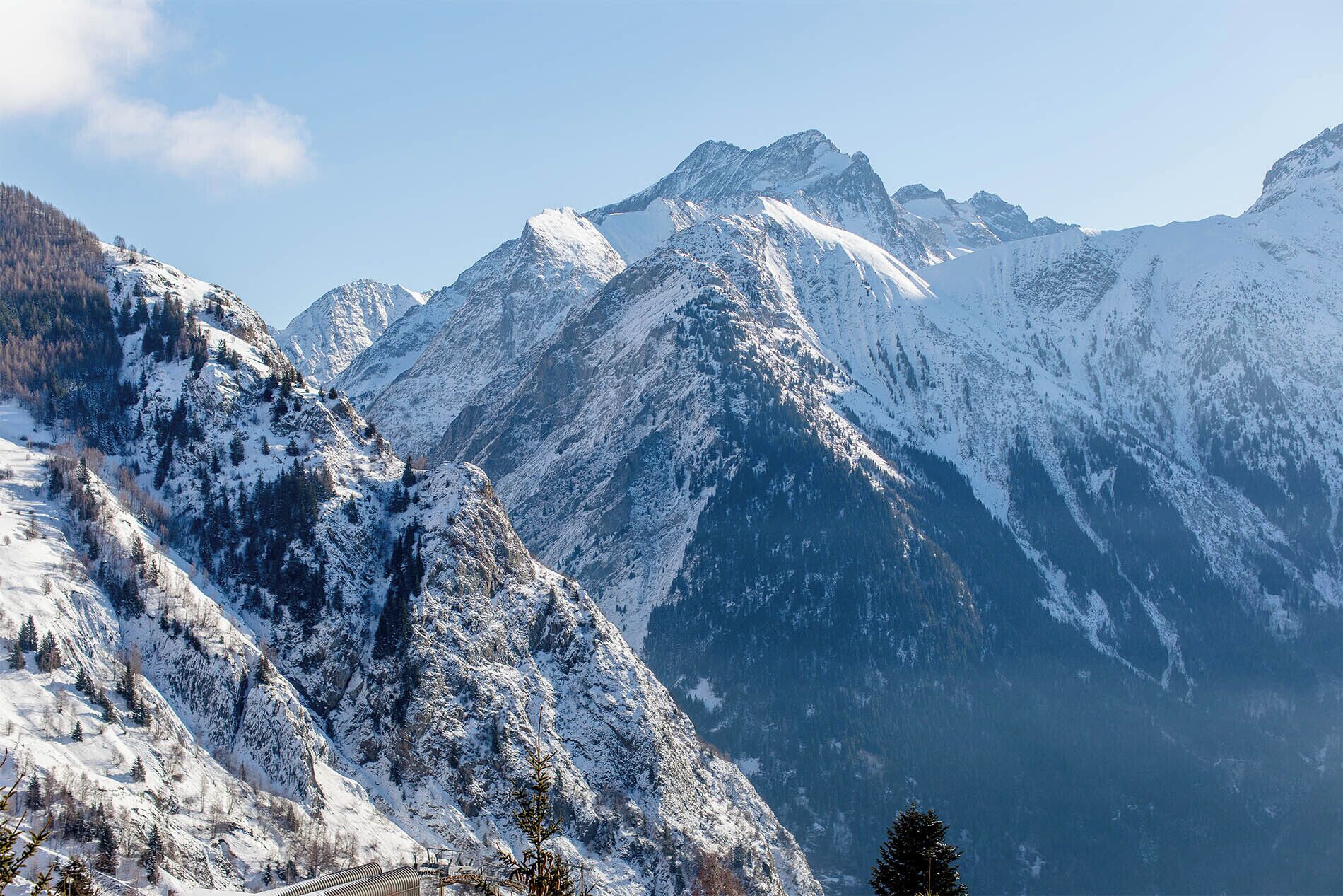 A mountainous landscape with snow-covered peaks and a ski lift visible in the foreground.