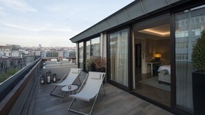 A modern hotel balcony with lounge chairs, a small table, and potted plants. - 10 Karakoy Istanbul - Special Class (Istanbul)
