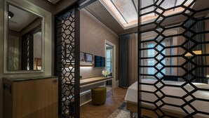 A modern hotel room with a wooden cabinet, a desk with a vase of flowers, a bed with a geometric-patterned screen, and a large mirror. - 10 Karakoy Istanbul - Special Class (Istanbul)