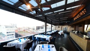 A restaurant with tables set for dining, a bar area, and a view of the cityscape. - 10 Karakoy Istanbul - Special Class (Istanbul)