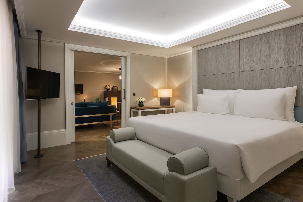 Une chambre d’hôtel moderne équipée d’un grand lit, d’un canapé, d’une télévision à écran plat, d’un bureau et d’une lampe.