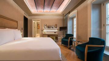 Habitación de hotel con una cama grande, un escritorio, dos sillas, un televisor y obras de arte en la pared.