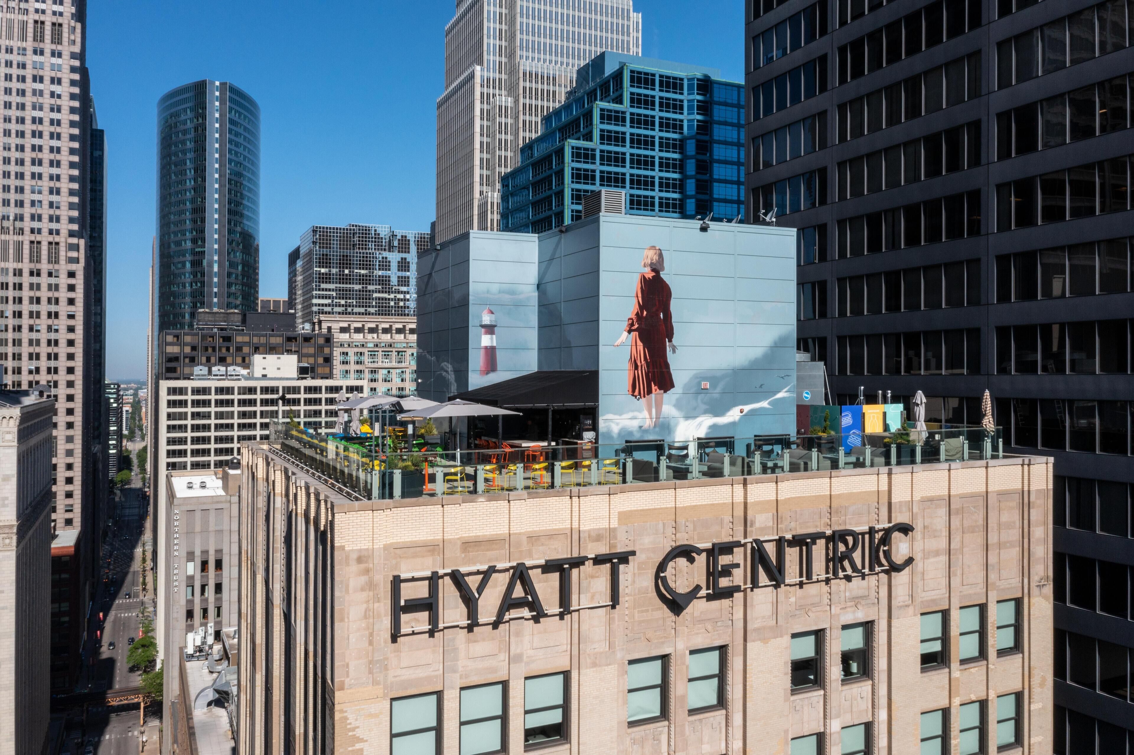 A hotel building with a large mural of a person on the side, surrounded by other high-rise buildings.