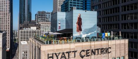 A hotel building with a large mural of a person on the side, surrounded by other high-rise buildings.