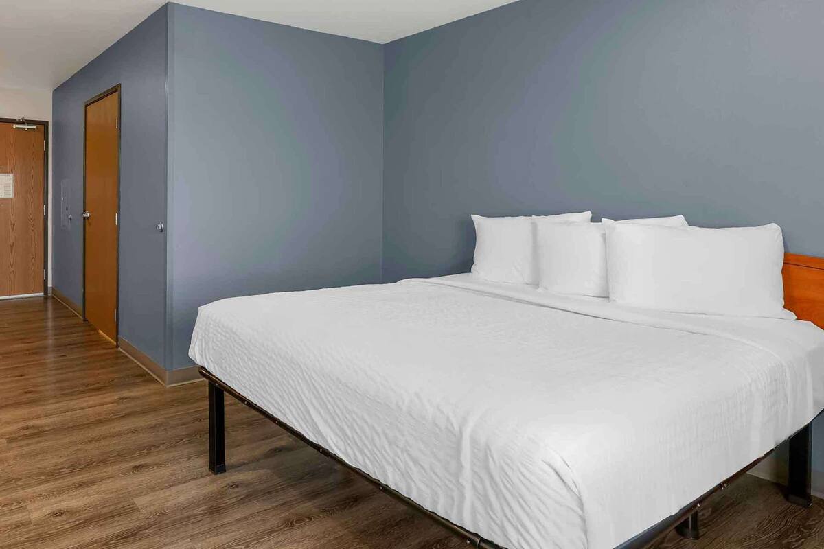 A hotel room with a large bed, a wooden floor, and a blue wall.