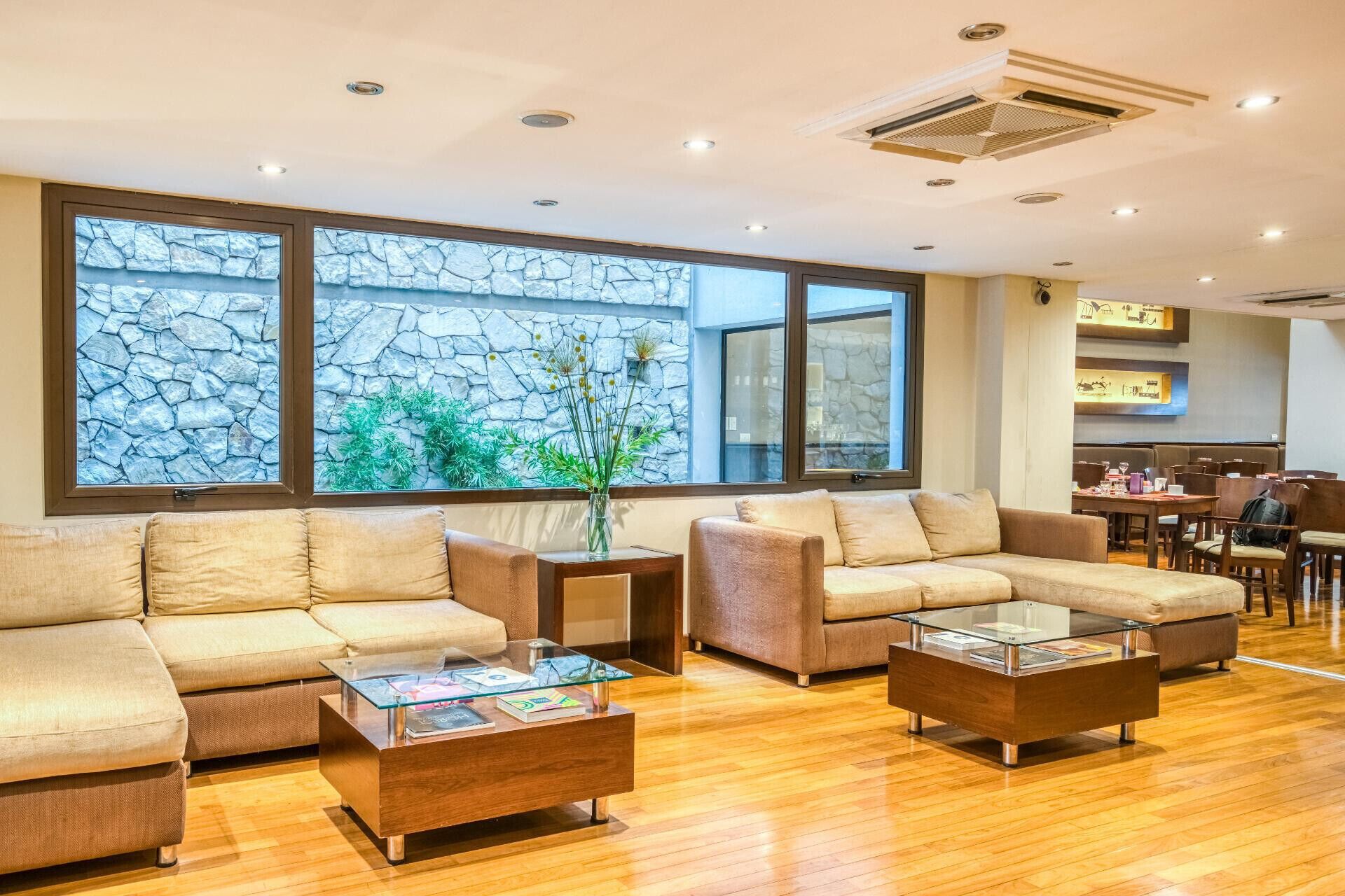A modern living area with sofas, a coffee table, and a view of a stone wall and greenery.